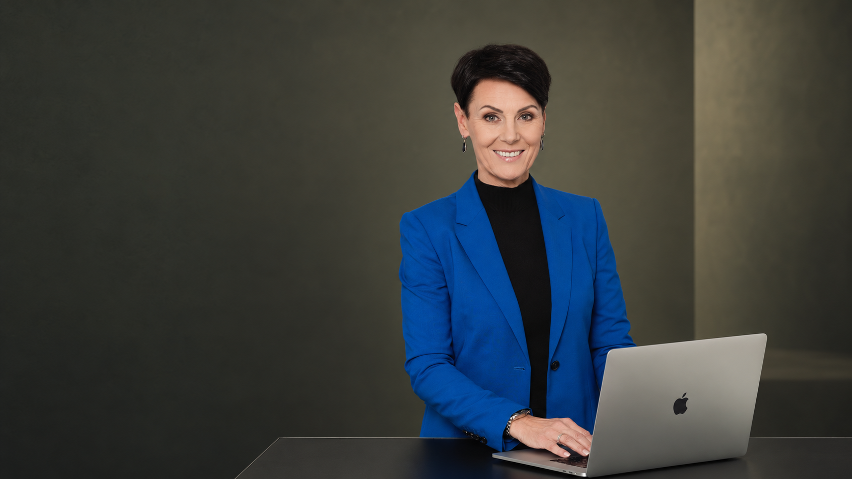 Corinne Häusler im blauen Blazer an ihrem Arbeitsplatz