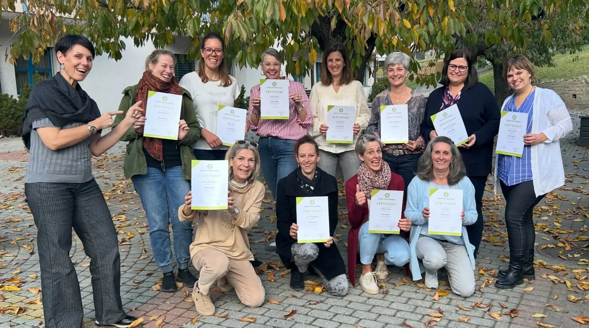 Corinne Häusler mit Teilnehmenden einer Ausbildung und ihren Zertifikaten